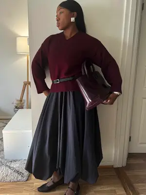 Woman wears beige cashmere sweater while taking mirror selfie