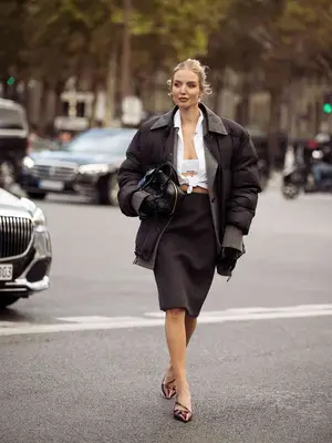 Woman wears white bra top and tied button-down, gray blazer, brown bomber, black midi skirt, and burgundy pointed-toe shoes