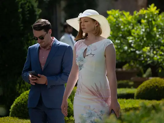 Sarah Snook wears a floral dress and wide brimmed woven ivory hat
