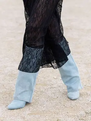 Close-up of person wearing light blue denim foldover boots and black lace midi skirt