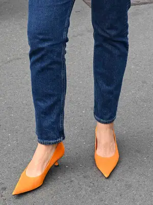 Close-up of woman wearing dark wash jeans and silver pointed-toe kitten heels