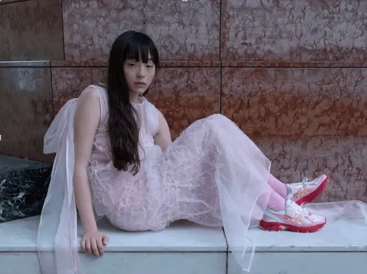 Model wearing a pink dress and bright sneakers