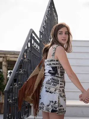 Beatrice Granno in The White Lotus wears a printed dress and a woven tote bag with fringe
