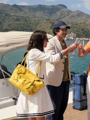 Aubrey Plaza wears a white skirt, cardigan, and a large yellow handbag