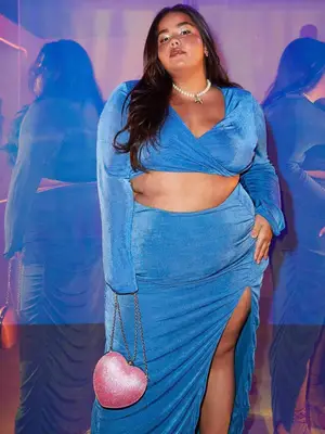 Priscilla Del Castillo wears a blue crop top and skirt set on a blue and pink background
