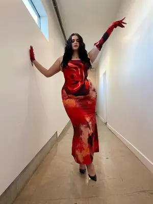 Barbie Ferreira wears a red rose print maxi dress, one opera glove and one short glove, and black pumps