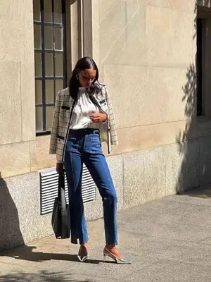Jasmine Tookes wears a tweed jacket, white blouse, jeans, and silver pumps