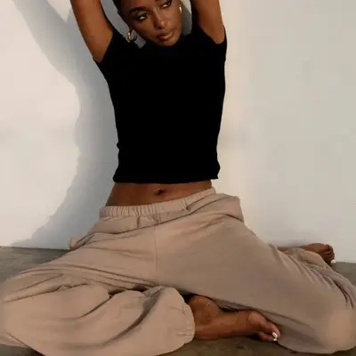 Model sitting down wearing a black tee and tan joggers 