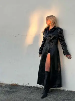 Renee Rapp wears a leather trench coat, black and white athletic shorts, and knee high boots