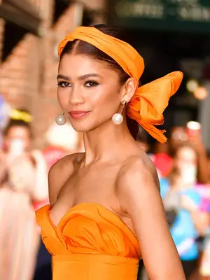 A woman outside by palm trees with the sun hitting her and she