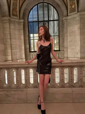 Lola Tung wears a black sequin dress, black purse, and black platform heels
