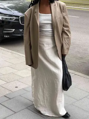 Woman wearing beige blazer, gray knit tank top, and linen maxi skirt