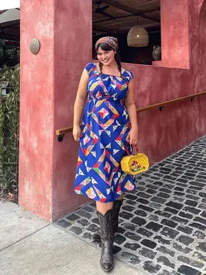 Kacey Musgraves wearing a white babydoll dress with a blue bow in front, plus white and blue snakeskin cowboy boots