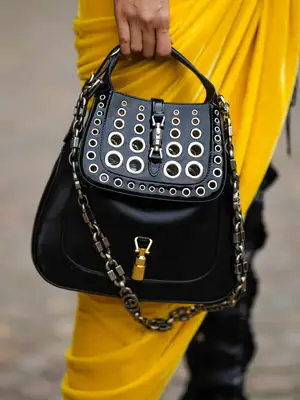 Close-up of woman wearing yellow and carrying black handbag with metal accents