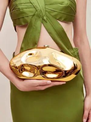 Close-up of woman wearing a green dress and carrying a gold clutch