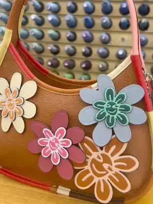 Close-up of brown Coachtopia bag with colorful leather trim and flower appliques