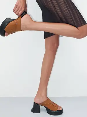 model wearing heeled black and camel sandals 