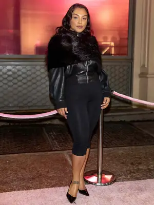 Paloma Elsesser poses for a photo wearing a fur top, leather jacket, capris, and heels