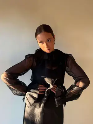 Laufey wears a sheer ruffled black blouse
