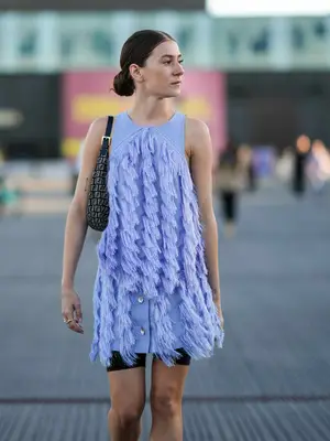Woman wearing a blue fringe mini dress over black bike shorts, paired with Fendi handbag
