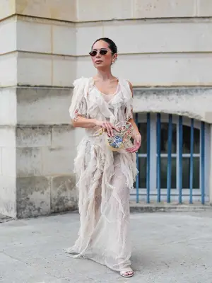 Marianna Hewitt wearing a ruffled sheer maxi dress, embroidered handbag, and sunglasses