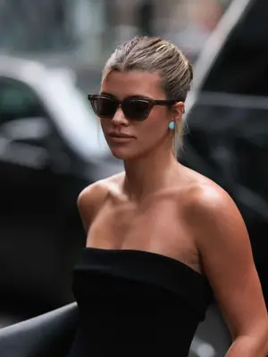 Sofia Richie Grainge wearing black strapless shirt, hair in bun, and cat eye sunglasses