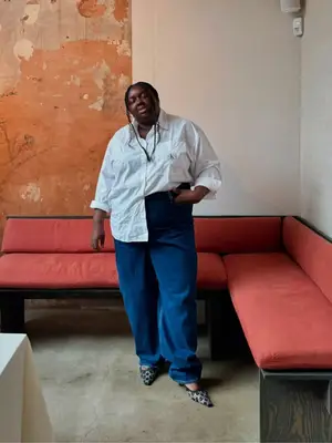 Abisola Omole wearing a white button-down shirt, jeans, and heels