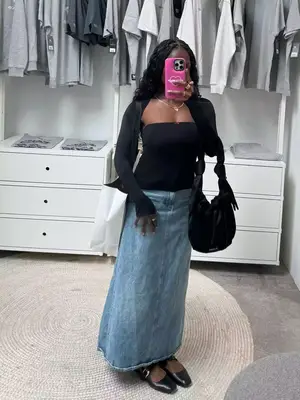 Toni Bravo wearing a long denim skirt, strapless black top, and shurg. She