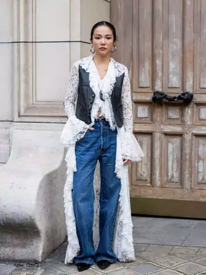 person wearing a pair of dark-wash jeans, lace duster, leather jacket, and heels