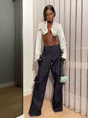 Adut Akech wearing cargo jeans, a silver top, and carrying a mini mint handbag