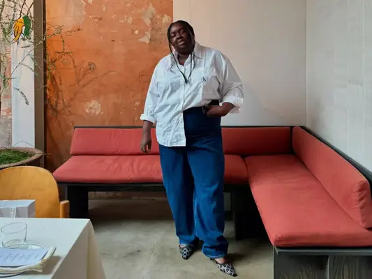 Abisola Omole wearing a white button-down shirt, dark wash jeans, and pointed-toe heels. 