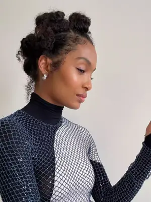 Yara Shahidi poses for a photo while wearing a turtleneck and blue knit mesh top