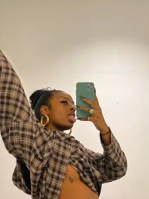 Justine Skye wearing a plaid button-down and gold hoop earrings