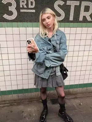 Taylor Momsen wears a denim jacket, gray skirt, tights, and boots