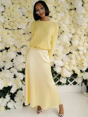 Jourdan Dunn wears a yellow sweater, silky slip skirt, white open-toe heels, and tiny sunglasses