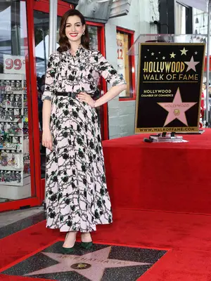 Anne Hathaway wearing a light pink and black printed Valentino dress with emerald green heels at her Hollywood Walk of Fame star ceremony