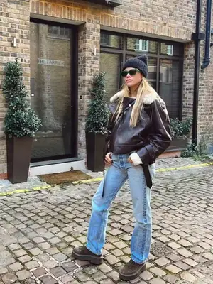 Sophia Richie Grainge wearing a brown leather jacket, light wash jeans, boots, and a beanie