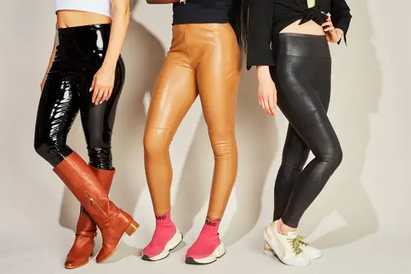 Group of people wearing faux leather leggings on a neutral background