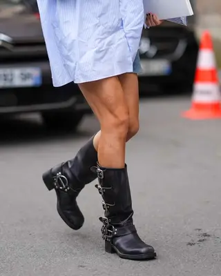 Close-up of person wearing motorcycle boots and striped shirt dress
