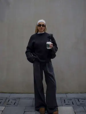 Morgan Riddle wearing white headband, black sunglasses, gray sweater, gray slacks, brown platform Uggs