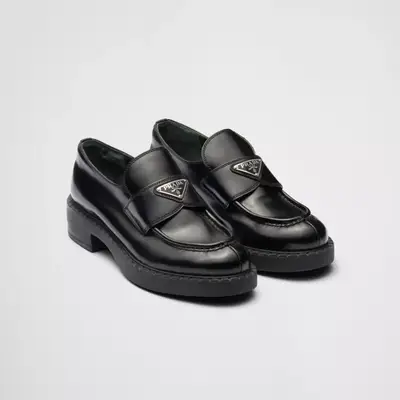 Prada black loafers with silver logo hardware against plain background