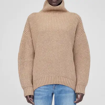 model wearing chunky tan knitted sweater and blue jeans, zoomed in