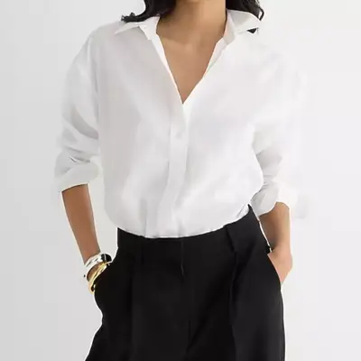 model wearing white button-up shirt tucked into black pants, zoomed in