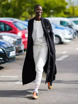 Model wearing a black wool maxi coat over a white athleisure outfit - MYM Beauty Fall/Winter Coat Trends