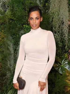 Rochelle Humes wearing white long sleeve dress and holding brown woven clutch