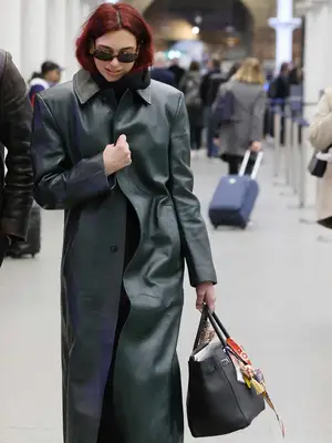 Dua Lipa holding handbag with charms and accessories