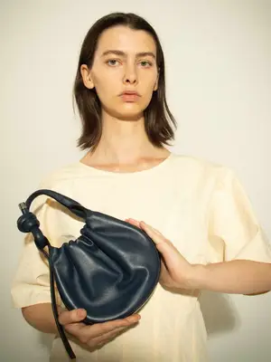 model holding navy blue handbag
