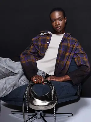 model wearing plaid shirt holding silver metallic handbag