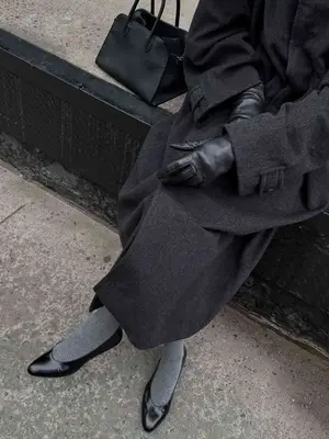 Woman wearing black ballet flats, gray socks, gray coat, and leather gloves