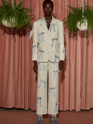 Model wearing off-white Tanner Fletcher suit with gray bows all over and gray oxford shoes